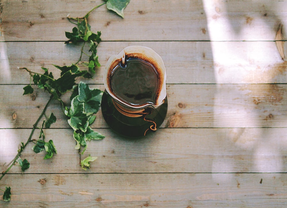 white plastic pitcher with black liquid on wooden surface