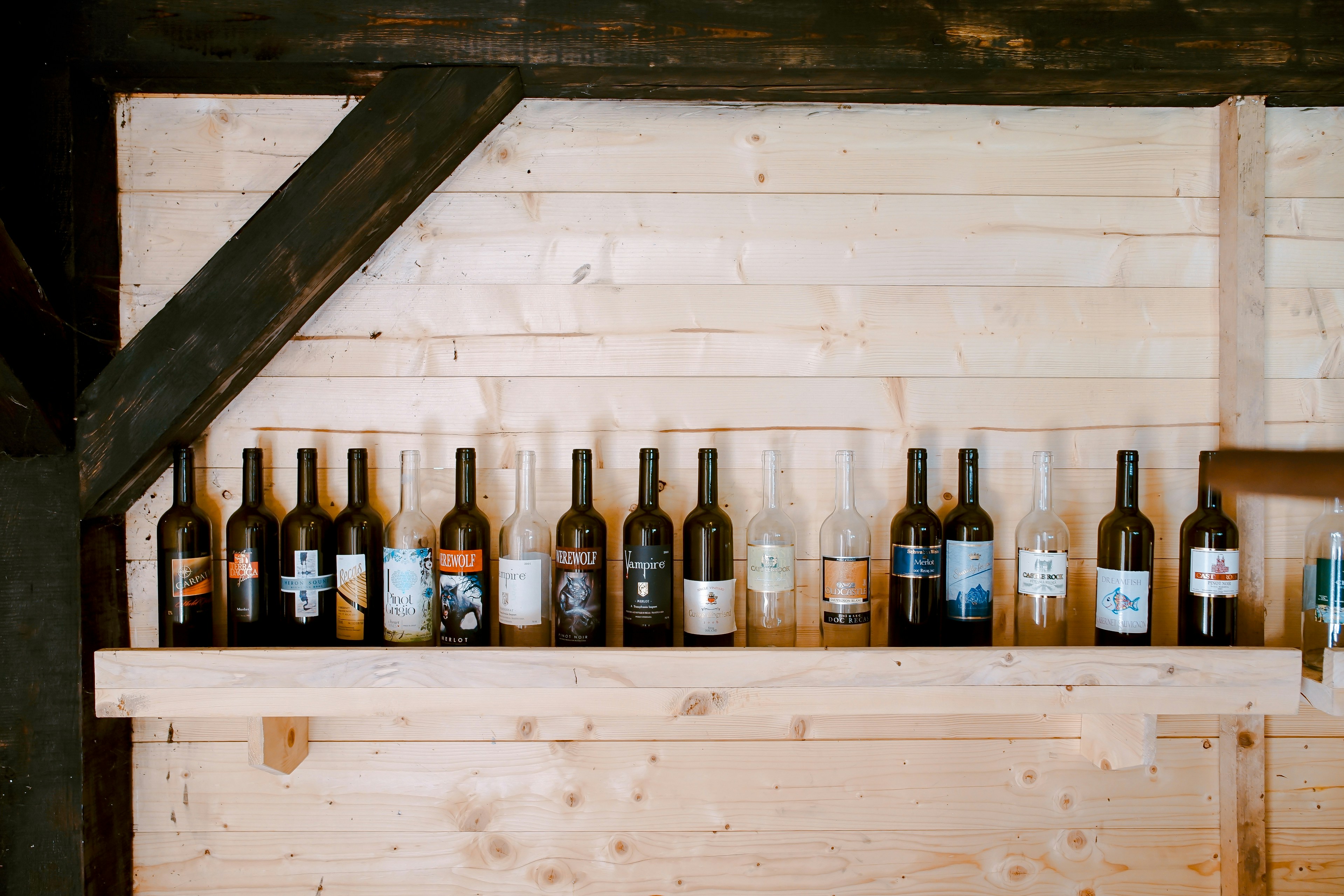 Wine bottles lined up on a rustic wooden shelf