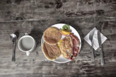 A cozy breakfast spread with eggs, bacon, and fresh fruit on a rustic table setting