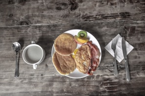 A cozy breakfast spread with eggs, bacon, and fresh fruit on a rustic table setting