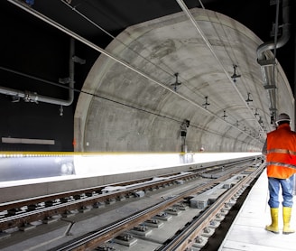 man standing beside train rail