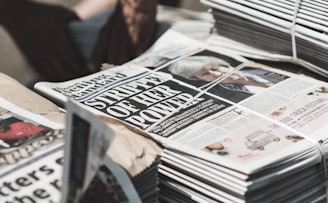 shallow focus photography of piles of newspapers