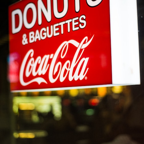 close photography of Donuts & Baguettes Coca-Cola signage