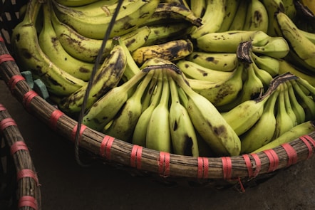 A wicker basket filled with bunches of ripe yellow bananas, some of which have dark spots on their peels.