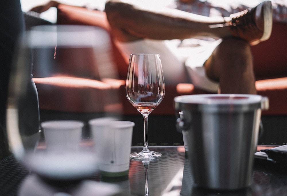 Copa de vino, cubo de hielo y dos tazas blancas sobre la mesa