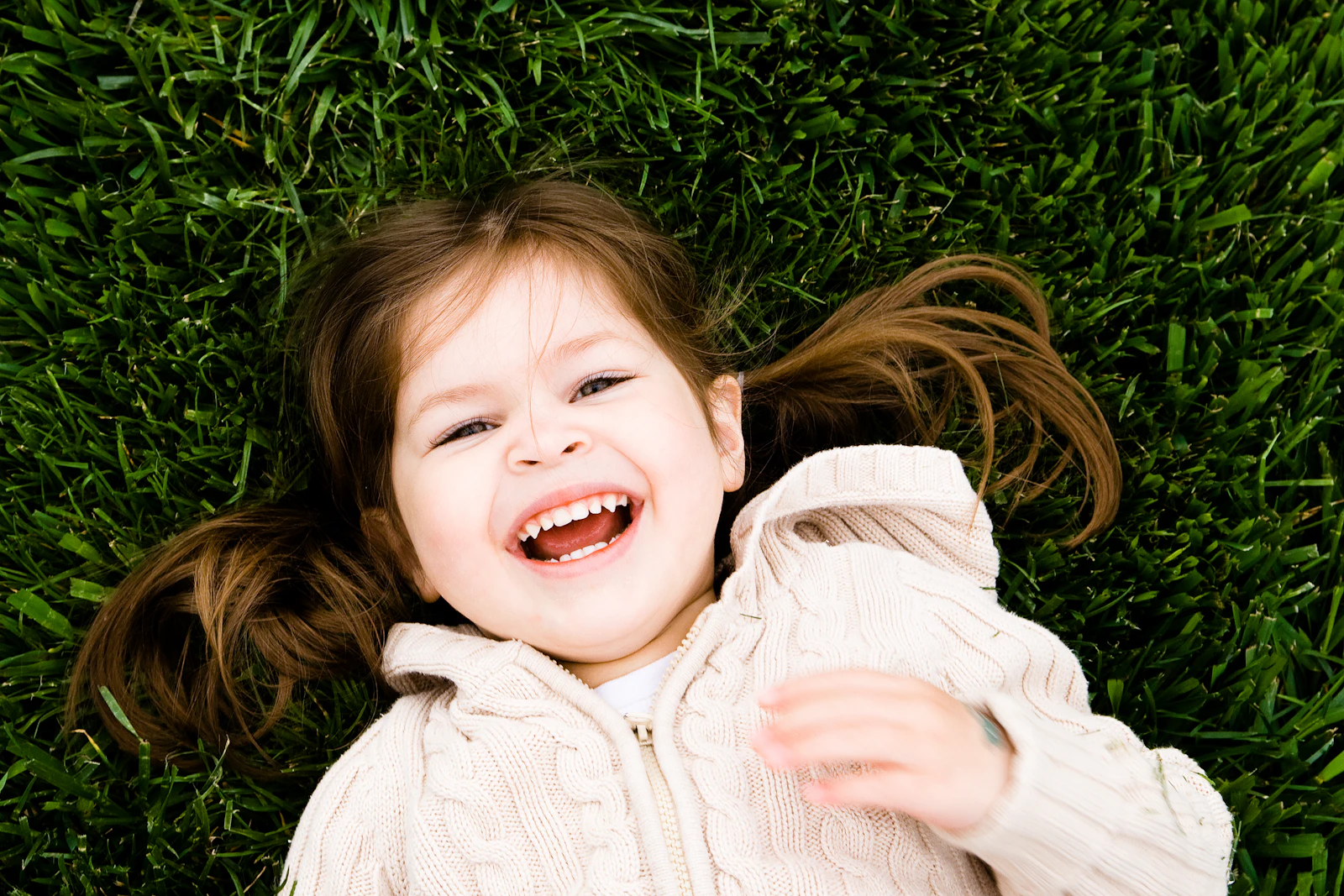 A little girl laughing as she lies in the grass