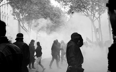 Volunteers wearing black masks and hoodies moving through misty streets with backpacks full of supplies.
