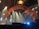 The image features a stage setup with theatrical lighting. A large, ornate archway frames the background, illuminated by multiple spotlights aiming in various directions. Some stage ropes are visible in the foreground, and a hanging lamp is situated above the archway. The overall ambiance suggests a theater or concert setting, with mist or fog possibly enhancing the lighting effects.