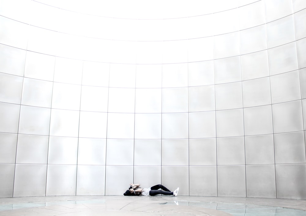 white and black short coated dog lying on white floor tiles