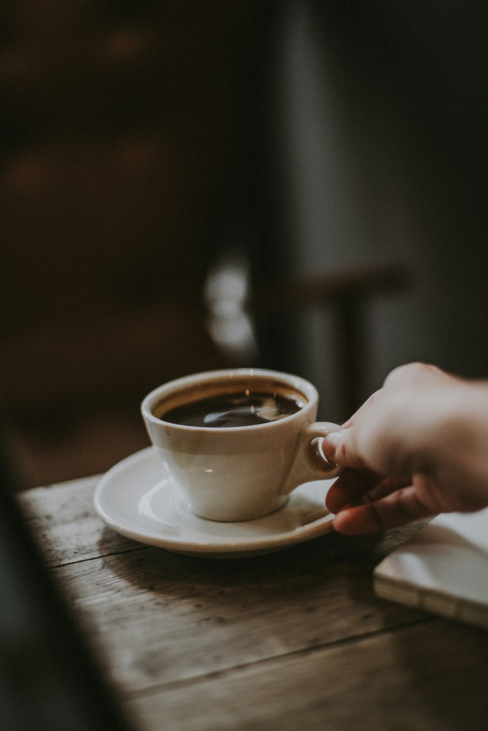 person holding white ceramic cup with liquid