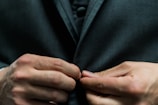 person holding black suit jacket button