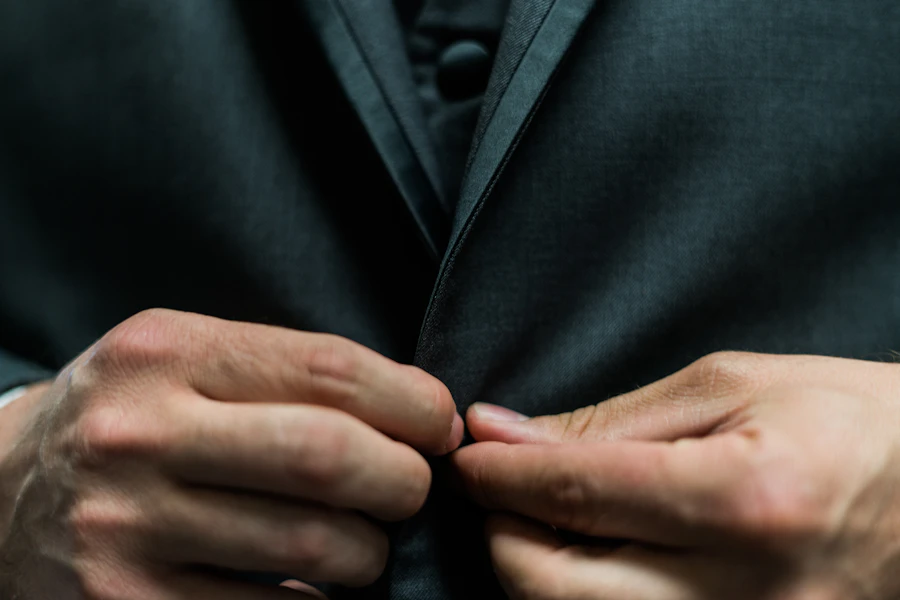 Mão ajustando a lapela de um blazer preto