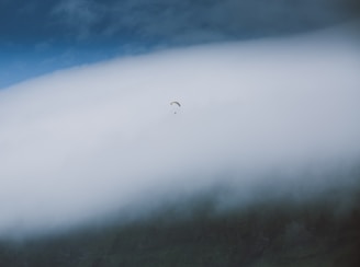 A vibrant scene of a lone character gliding above fluffy clouds at sunset.