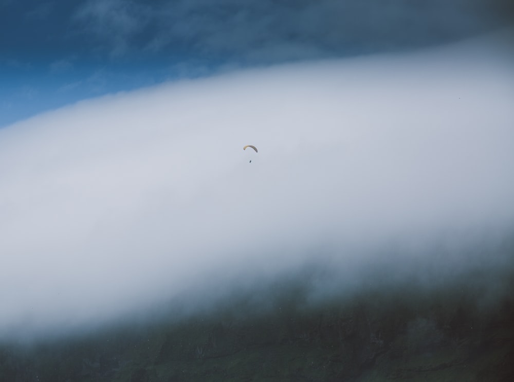 a paraglider is flying through the clouds in the sky
