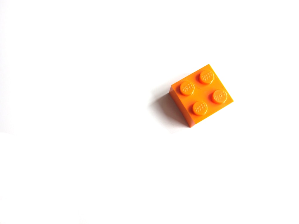 juguete de mega bloques naranja sobre superficie blanca