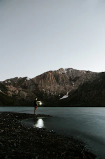 Hand gripping an Olight torch with a soft mountain backdrop at dusk.