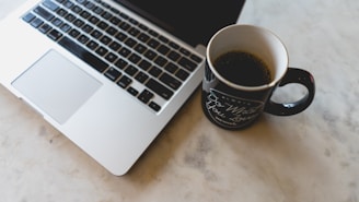 coffee in mug beside MacBook Pro