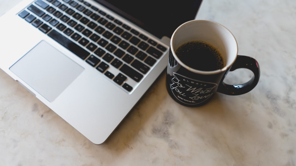 coffee in mug beside MacBook Pro