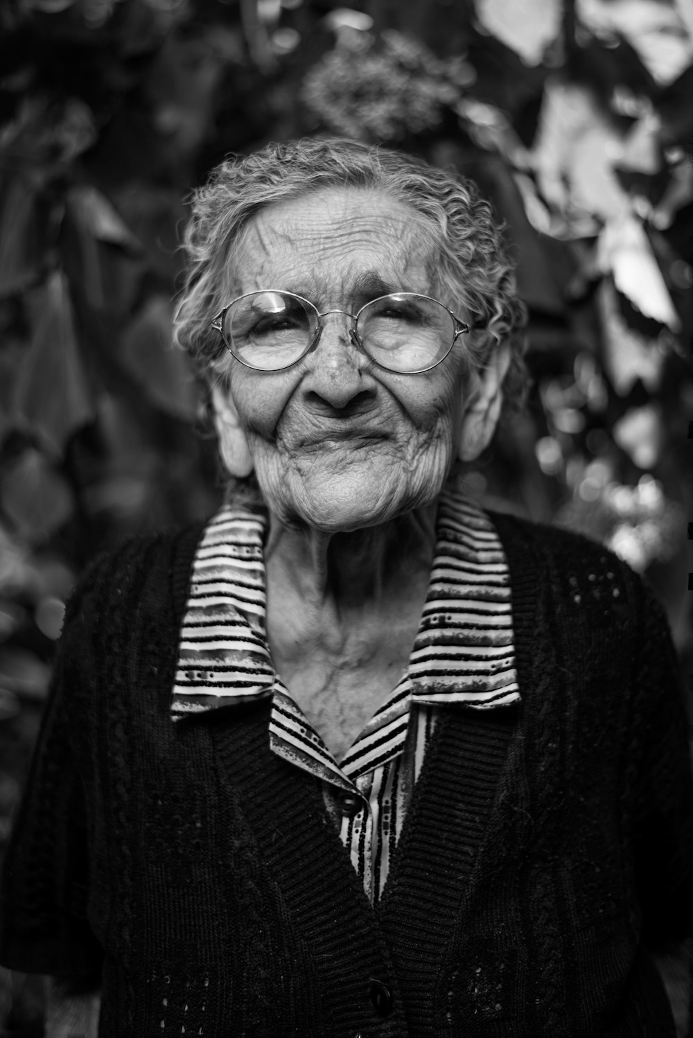 An old retired women with circular glasses in a black and white close-up macro portrait.