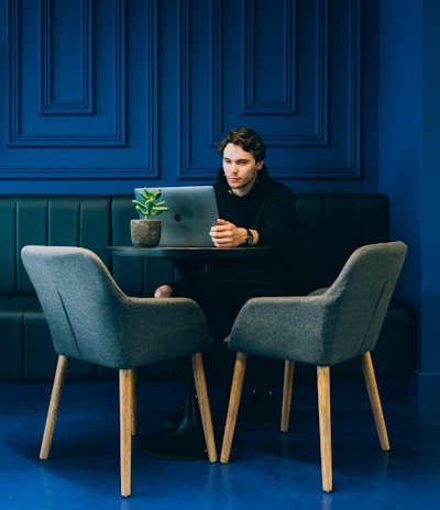 man sitting on couch with looking at his MacBook on table