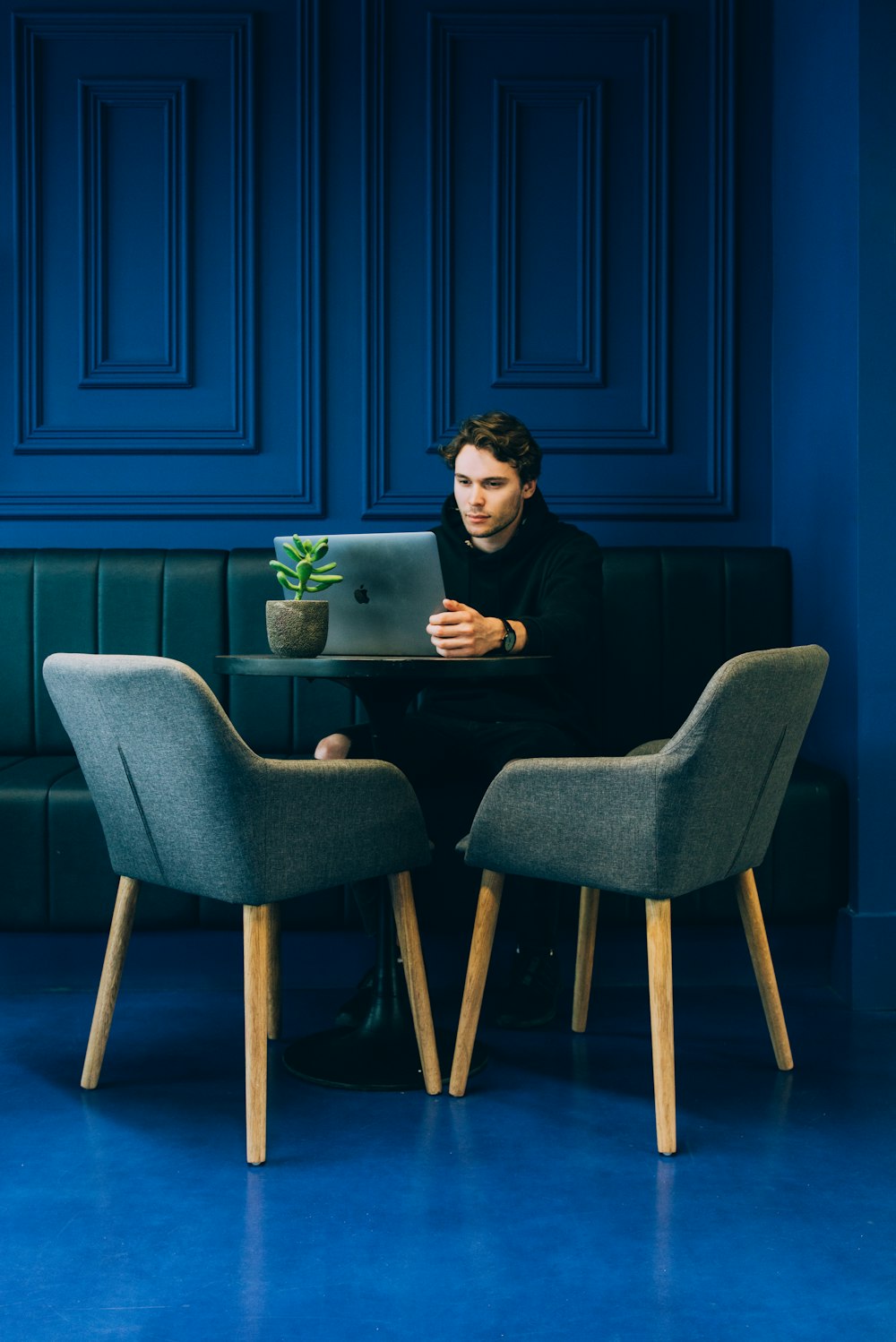 man sitting on couch with looking at his MacBook on table