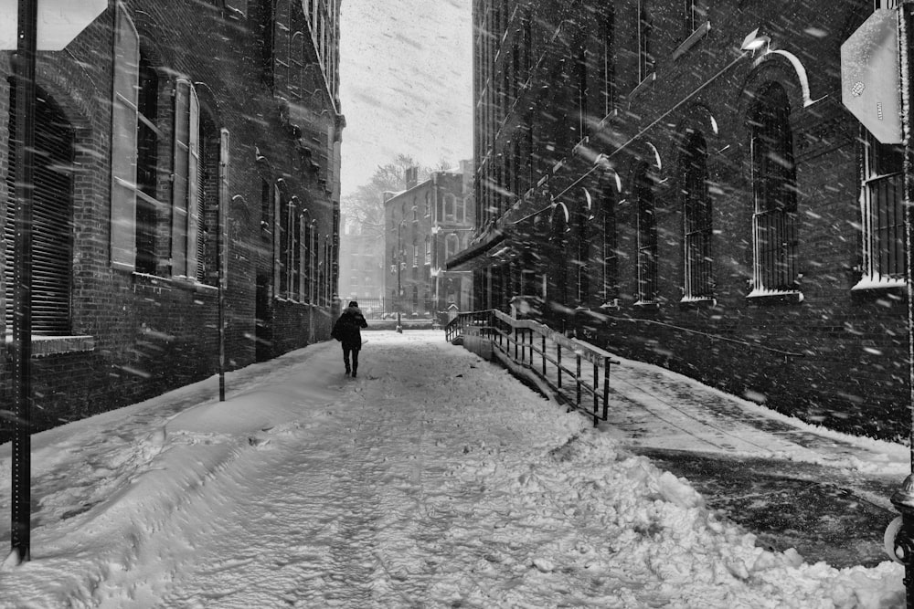 grayscale photo of person walking on snow covered road