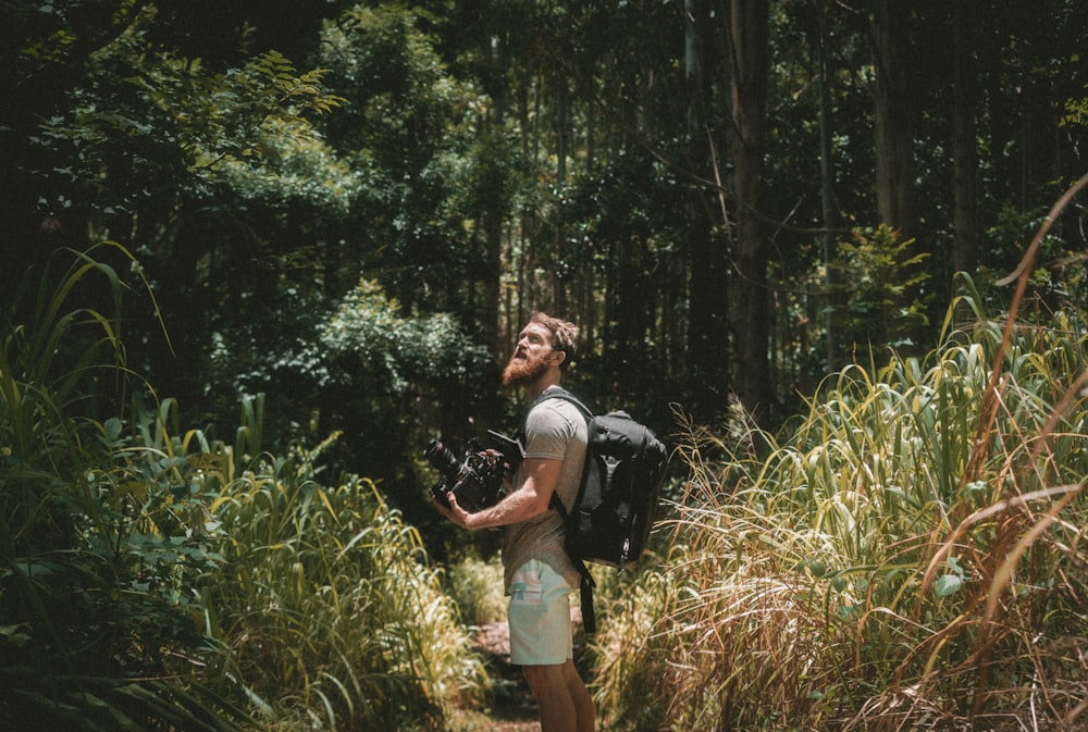 hombre sosteniendo la cámara en el bosque
