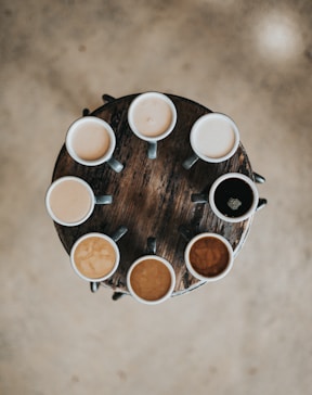 flat lay photography of eight coffee latte in mugs on round table