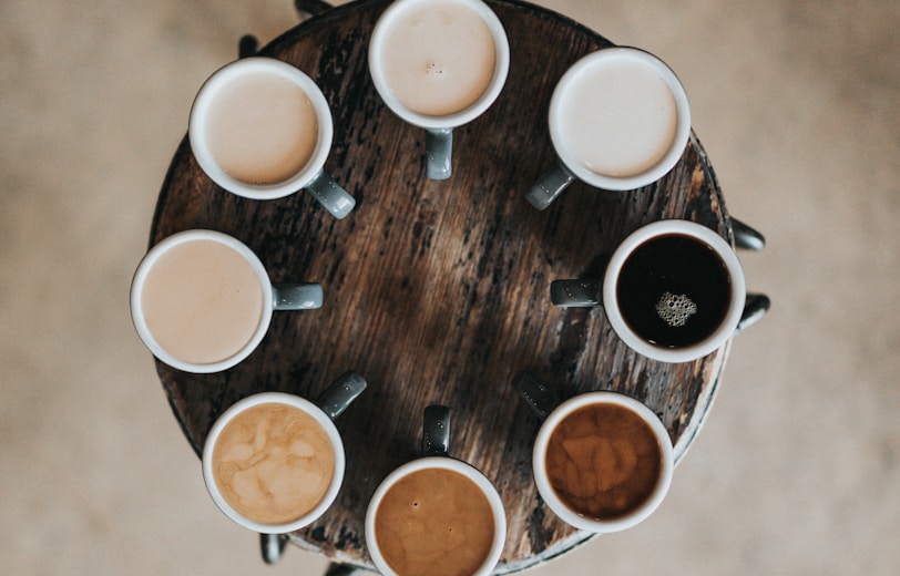 flat lay photography of eight coffee latte in mugs on round table
