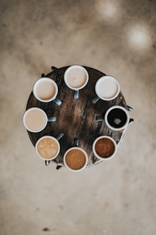 flat lay photography of eight coffee latte in mugs on round table