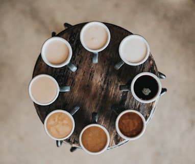 flat lay photography of eight coffee latte in mugs on round table