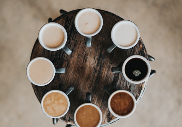 flat lay photography of eight coffee latte in mugs on round table