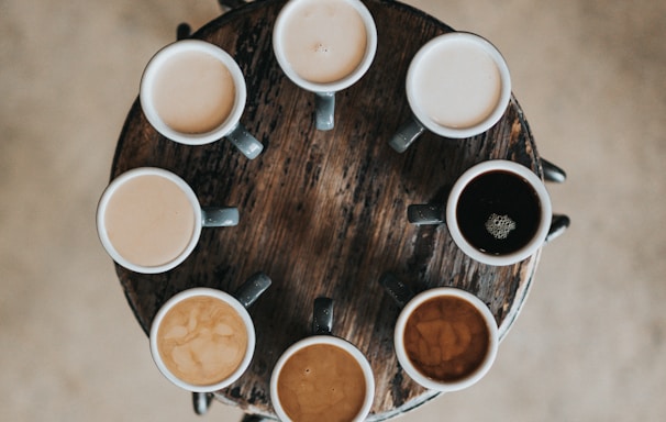 flat lay photography of eight coffee latte in mugs on round table