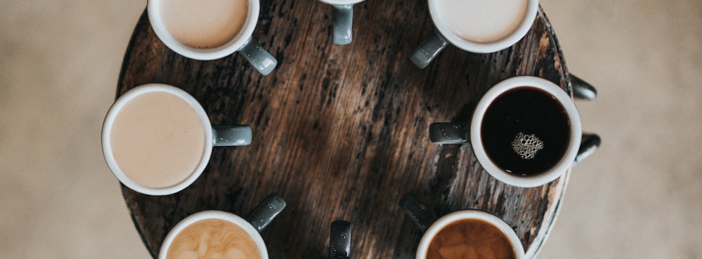 flat lay photography of eight coffee latte in mugs on round table