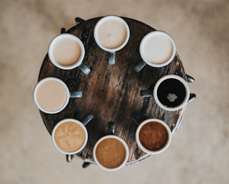 flat lay photography of eight coffee latte in mugs on round table