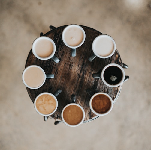 flat lay photography of eight coffee latte in mugs on round table