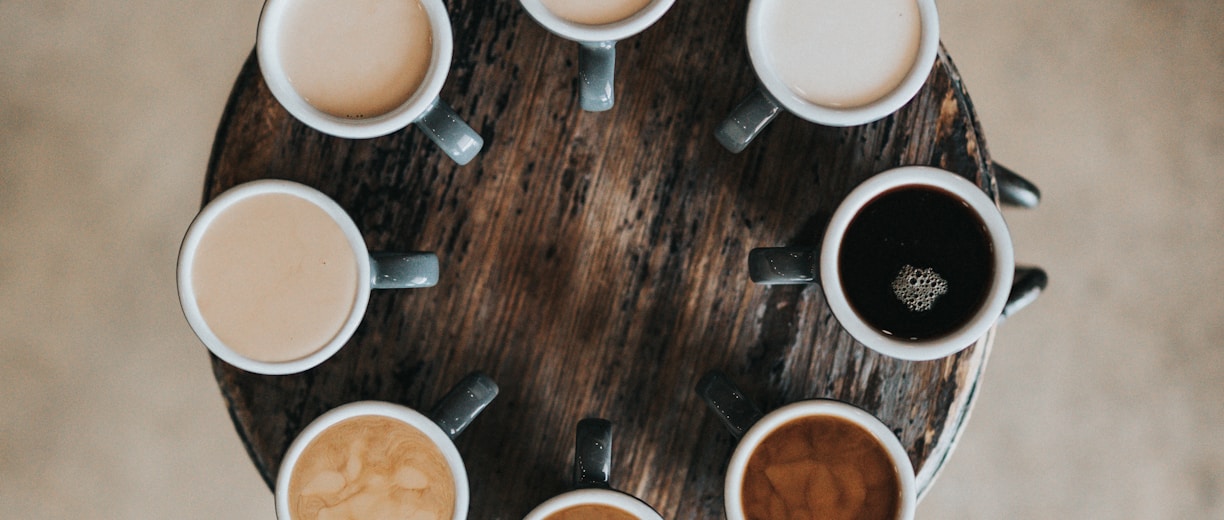 flat lay photography of eight coffee latte in mugs on round table