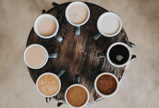 flat lay photography of eight coffee latte in mugs on round table