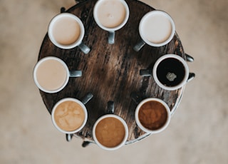 flat lay photography of eight coffee latte in mugs on round table