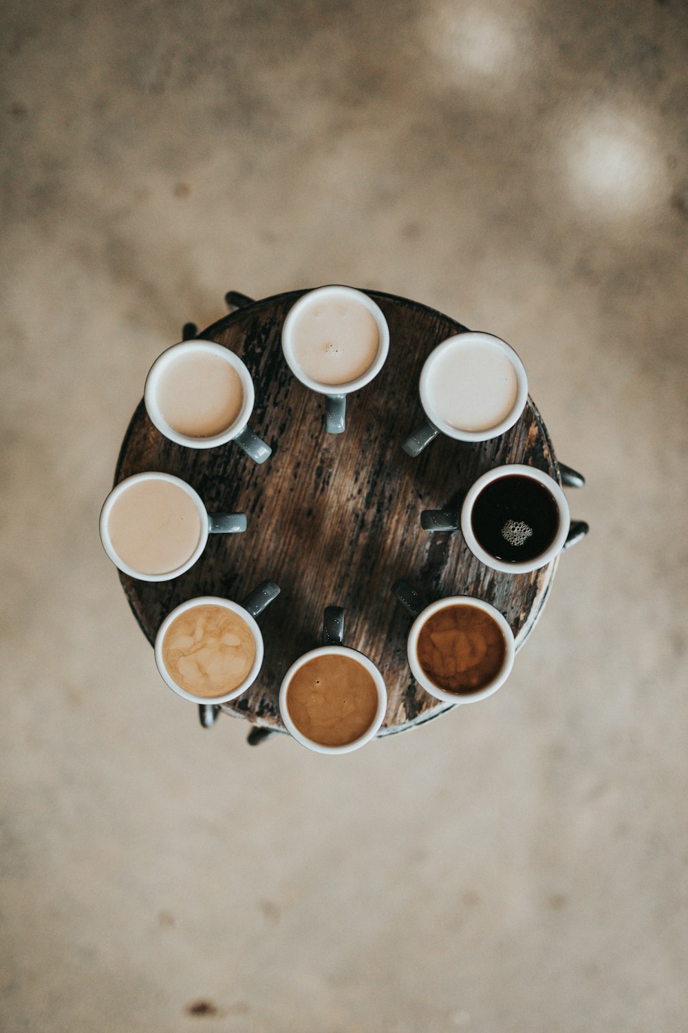 Fotografía plana de ocho cafés con leche en tazas sobre mesa redonda