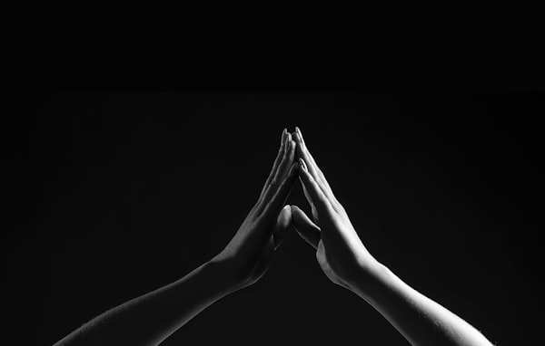 two hands touching against a black background