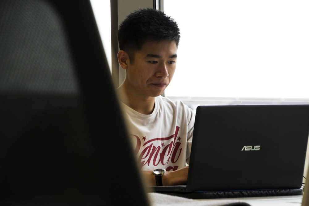 man sitting while using Asus laptop