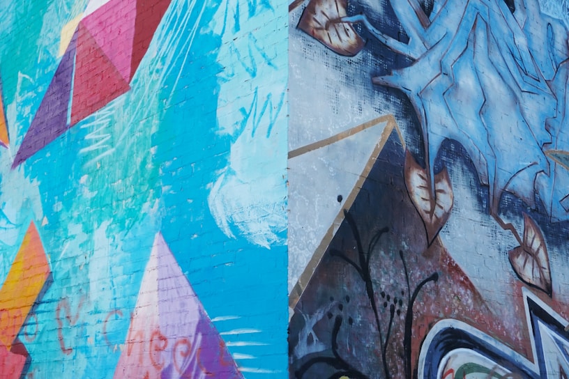 A vibrant urban mural blending colorful geometric shapes with natural elements on a city wall.