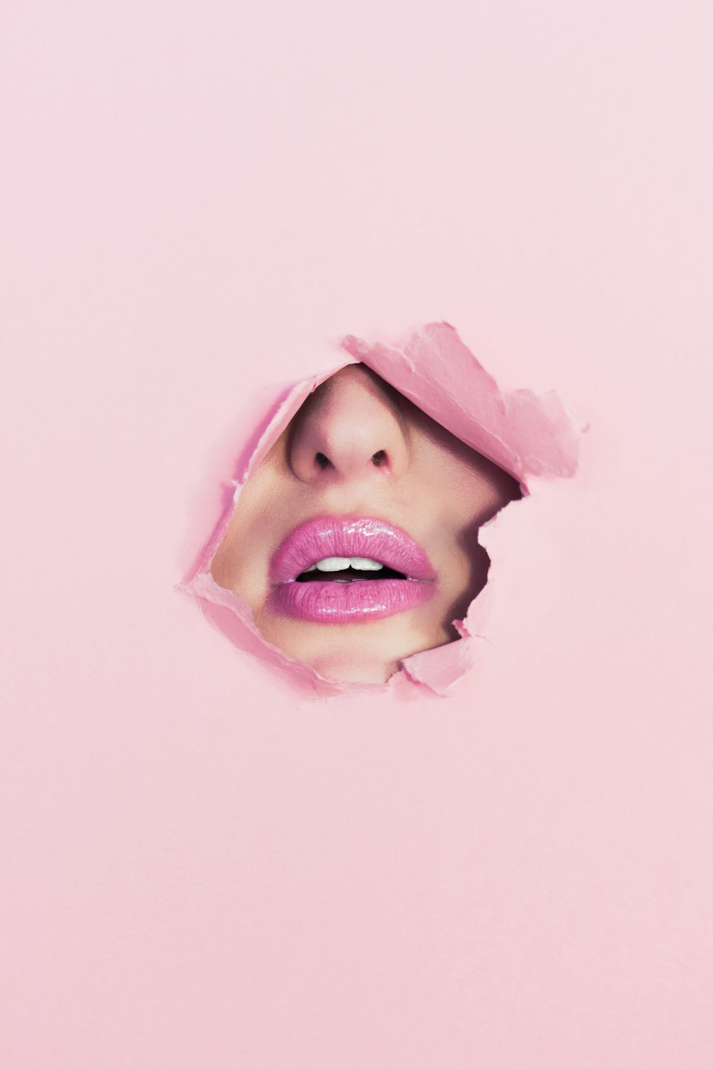 woman with pink lipstick on hole of pink paper
