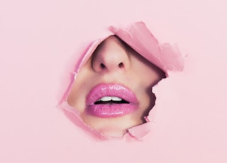 woman with pink lipstick on hole of pink paper