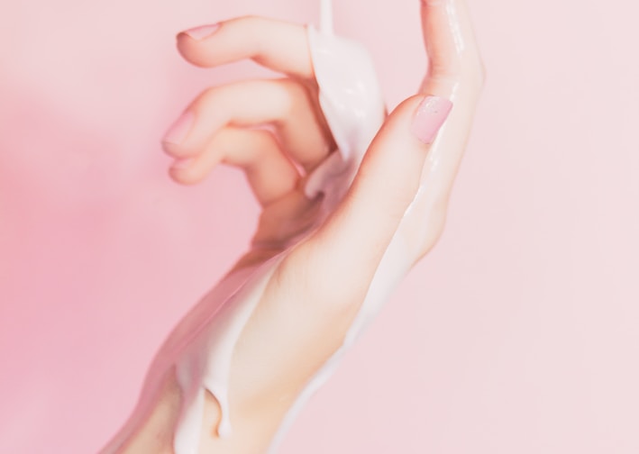 a woman's hand holding a bottle of lotion