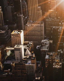 An aerial view of a revitalized East London neighborhood featuring clean lines and dark-toned buildings highlighted by golden light.
