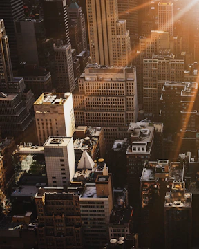 An aerial view of a revitalized East London neighborhood featuring clean lines and dark-toned buildings highlighted by golden light.