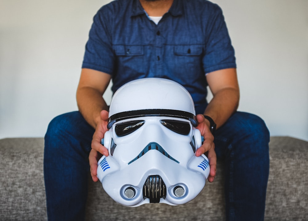 person sitting on sofa holding Stormtrooper helmet