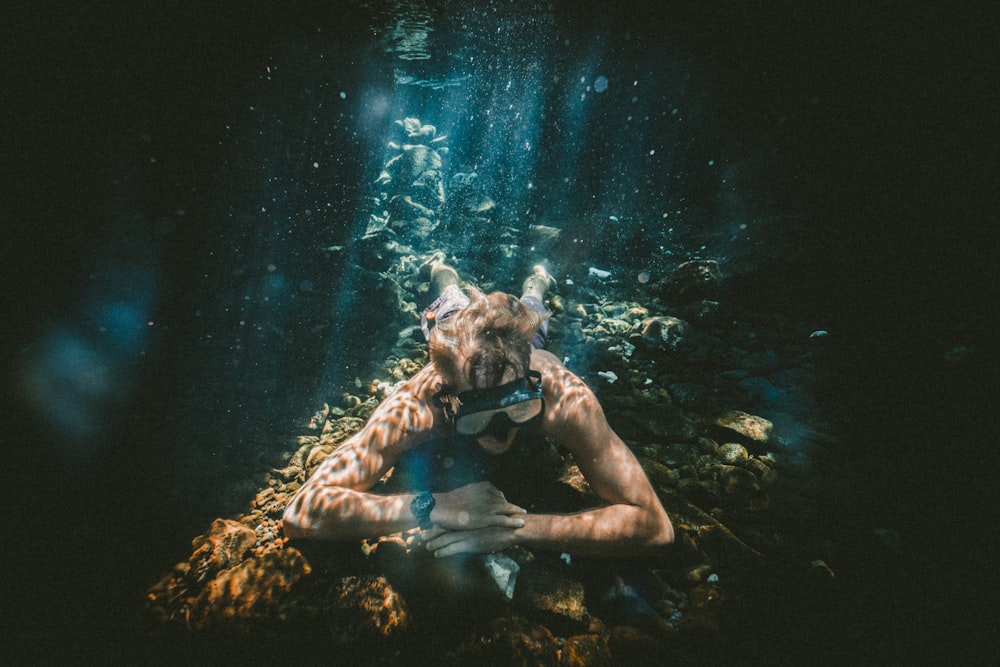 Foto di un uomo sott'acqua che indossa occhialini da nuoto neri